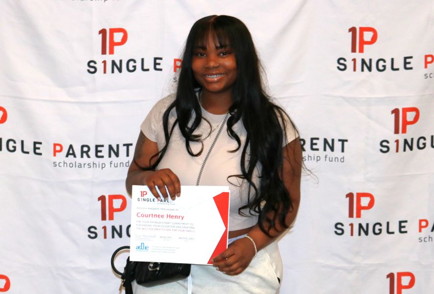 Woman Courtnee receives her single parent scholarship in front of an ASPSF banner.