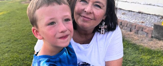 Kim Paul Williams holds her grandson in the grass.
