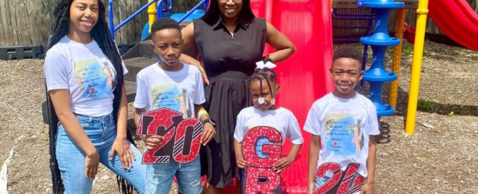 Kimberly Broadway and her four kids stand in a playground. The kids are holding signs that say "2024 Grad."