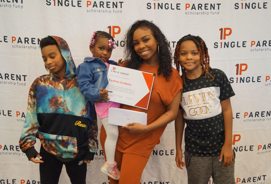 Single mom with her kids stands in front of an ASPSF banner.
