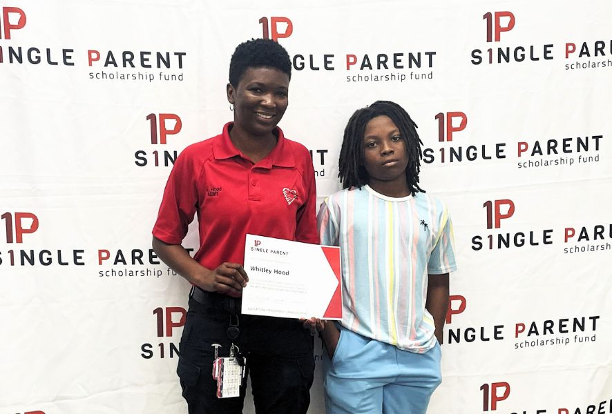A woman in EMS uniform and her son stand in front of an ASPSF banner.