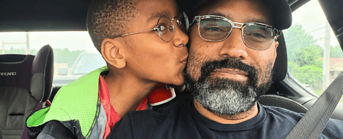 Kwami's son kisses his cheek in the car