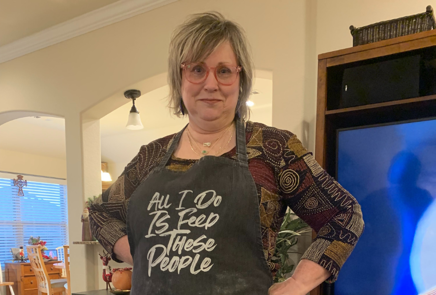 Paige Wearing an Apron that says 'All I do is feed these people'