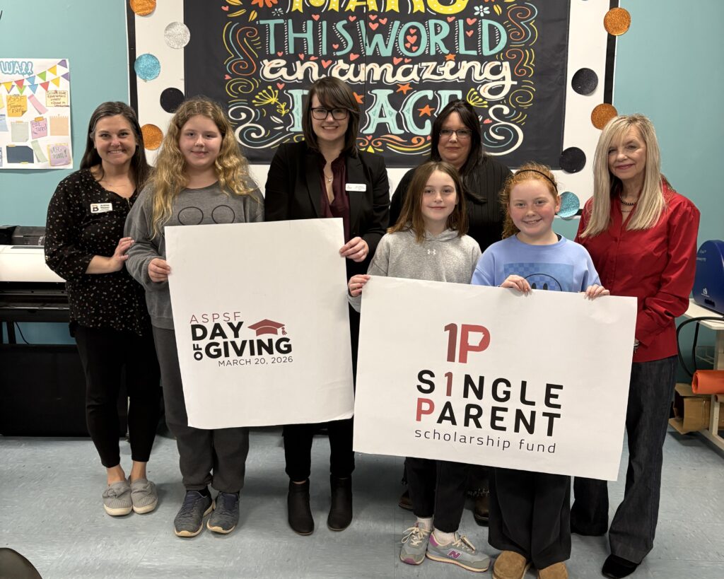 A group of 5th graders and adults hold signs for ASPSF and Day of Giving
