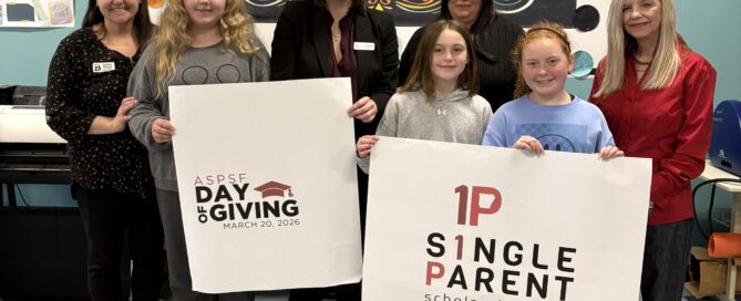 A group of 5th graders and adults hold signs for ASPSF and Day of Giving