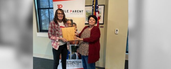Two women hold an arkansas shape