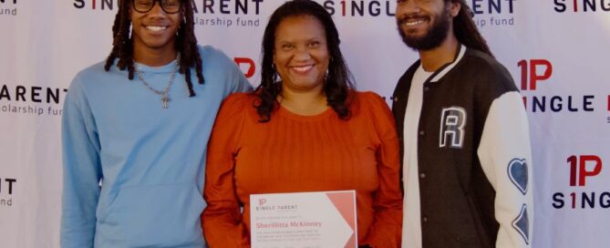 Mom holding certificate in the middle of her adult and teeage sons.