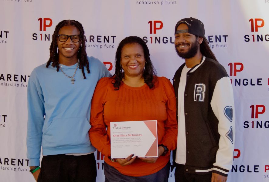 Mom holding certificate in the middle of her adult and teeage sons.