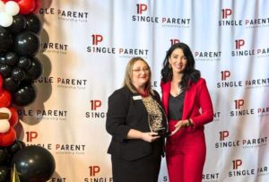 Jenn Morehead and Bailey Hutcheson hold an award in front of an ASPSF step and repeat