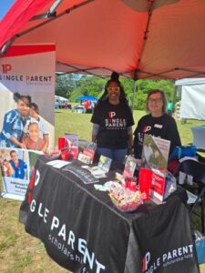 Amesha Peel and Carrie Allen stand in a tent with an ASPSF table