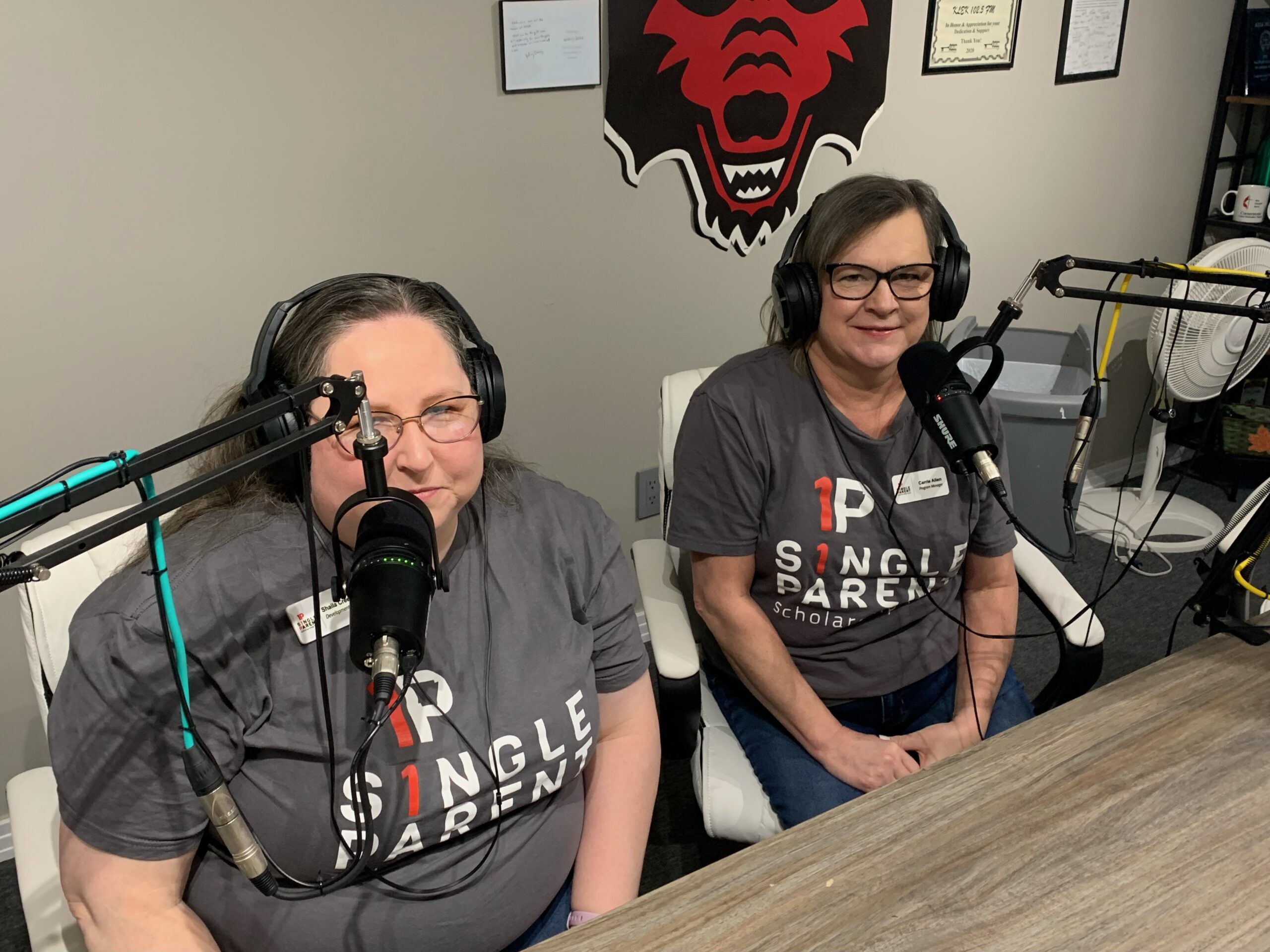 Two women with ASPSF tshirts on sit in a radio studio.